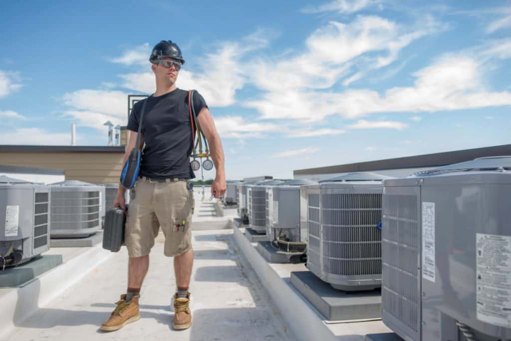 An HVAC technician examines multiple air conditioning units